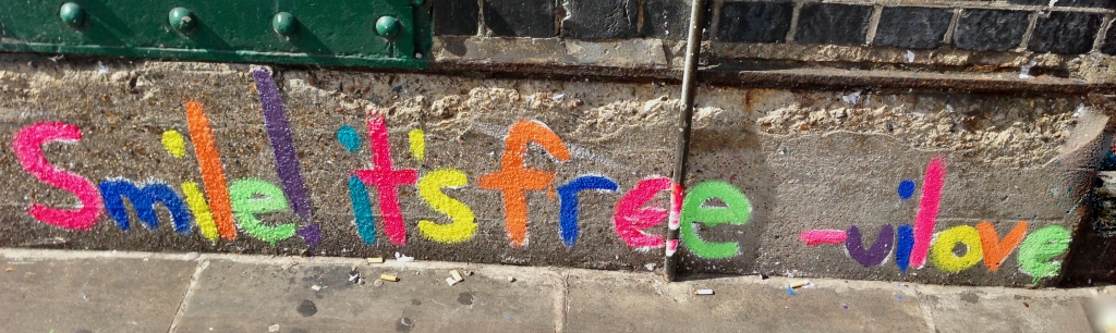Colourful graffiti reading 'Smile! it's free'
